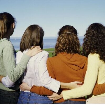 Vier stehende Frauen nebeneinander, die sich umarmen